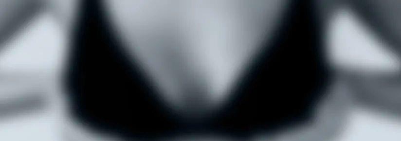 Recorte desfocado do colo de uma mulher na linha do sutiã